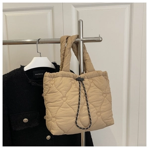 Detail of beige quilted tote bag featuring unique heart stitching and drawstring closure