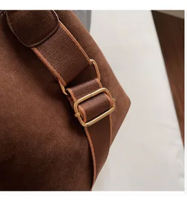 Detail of premium gold-tone metal buckle and brown suede texture on a vintage bucket bag