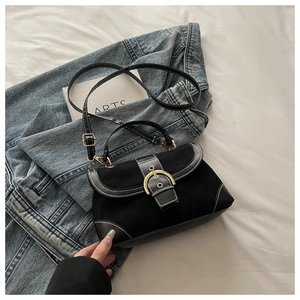 Detail of black suede shoulder bag with gold buckle on denim clothing background