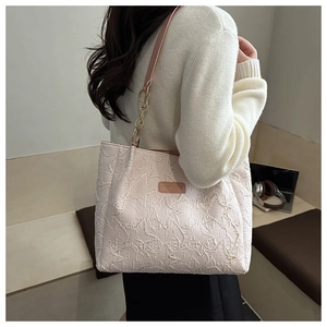 Détail d'un sac cabas texturé à motif d'étoiles avec bandoulière et plaque logo