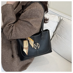 Detail of black tote bag with white stitching and decorative silk scarf on the handle