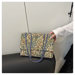 Nahaufnahme von Blumen-Jacquard-Stickerei und blauem Leder-Kettenriemen an der Tasche
