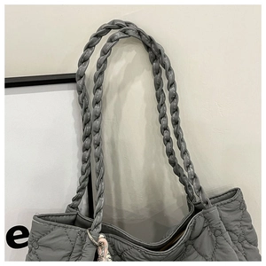 Close-up of heart-shaped quilting and sturdy woven handles on a grey nylon tote bag