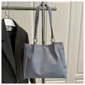 Detail view of large light blue tote bag with gold rings hanging on a metal rack