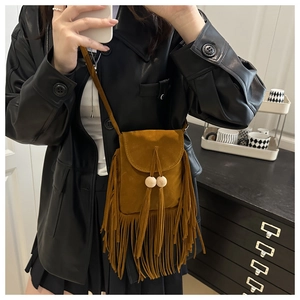 Détail d'un sac bandoulière en suédine marron avec de longues franges et billes en bois