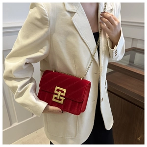 Detail of red velvet crossbody bag with quilted texture and gold chain strap