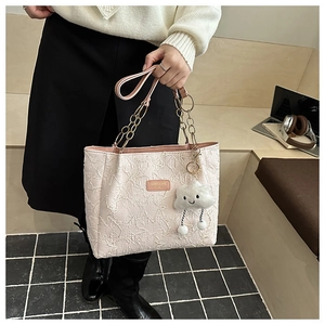 Détail du sac cabas rose clair texturé avec poignées en chaîne et charme nuage