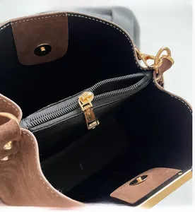 Detail of suede bucket bag interior with golden zipper compartment and magnetic snap