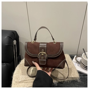 Detail of vintage brown suede crossbody bag with large gold buckle and stitching