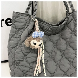 Detail of grey quilted heart tote bag with woven handle and plush bear charm accessory