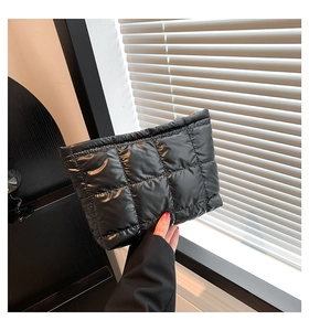 Détail d'une pochette matelassée noire avec finition brillante et fermeture éclair dorée