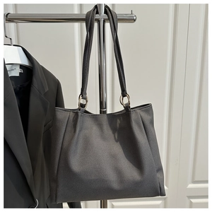 Detail of dark grey tote bag with cross-grain texture and golden ring connectors