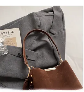 Detailed macro view of the brown suede bucket bag with leather handle and gold hardware