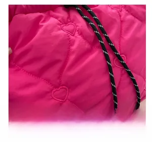 Macro shot of hot pink quilted fabric with heart stitching and woven cord details