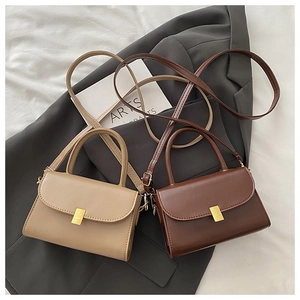 Detail of khaki and brown mini flap bags with gold metal buckles on a grey blazer