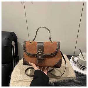 Detail of vintage caramel suede handbag with leather trim and gold buckle in lifestyle setting