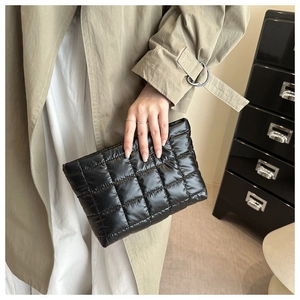 Détail d'une pochette matelassée noire en nylon brillant au fini doudoune