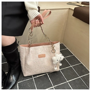 Détail du sac cabas rose clair avec textures frangées et charm nuage en peluche