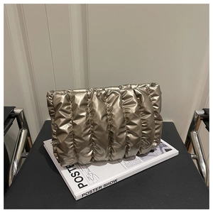 Detail of champagne gold quilted cloud bag with puffy metallic texture on a book