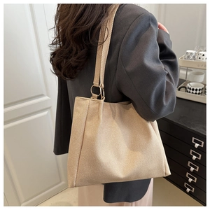 Detail of minimalist beige woven tote bag showing the wide strap and metal ring attachment