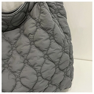 Close-up of gray quilted fabric with dense heart-shaped stitching and puffy texture