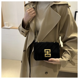 Detail of black suede crossbody bag with golden chain and stitched diagonal pattern