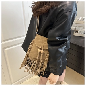 Détail d'un sac bandoulière en suédine marron avec de longues franges et perles en bois rétro