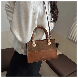 Detail of vintage square bag with leopard print panel and woven handle in warm brown
