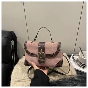 Pink matte suede and brown leather handbag with gold buckle on a beige sweater