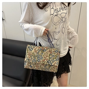 Nahaufnahme von Vintage-Blumen-Gobelinstoff und Goldkette am Damen-Handtasche