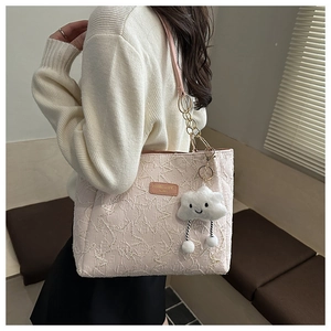Détail du sac cabas rose à motif d'étoiles avec chaîne dorée et breloque peluche à l'épaule