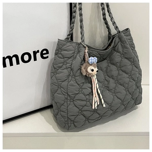 Close-up of heart-quilted grey tote bag with woven handles and pink ribbon plush charm