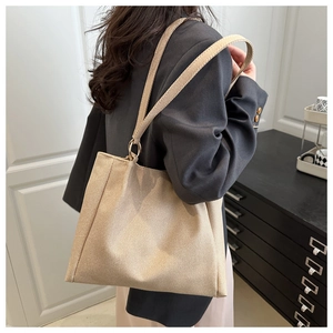 Close-up of the woven texture on a large beige tote bag worn by a model in a room