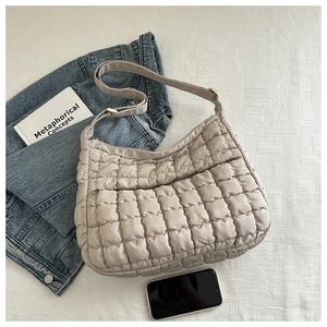 Vue détaillée du sac matelassé beige à texture nuage avec bandoulière et accessoires