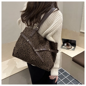 Grand sac fourre-tout léopard avec bandoulières en cuir marron porté à l'épaule