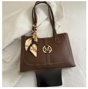 Brown leather tote with contrast stitching, silk scarf detail, and smartphone for size scale