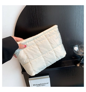 Détail de la pochette matelassée blanche avec texture douce et fermeture éclair