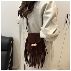 Détail d'un sac bandoulière en daim marron avec des franges et des perles en bois