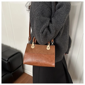 Detail of vintage brown textured leather handbag with gold metal handle and logo