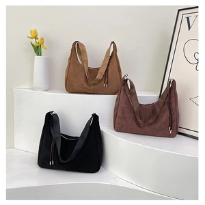Tre borse hobo in pelle scamosciata color kaki, marrone e nero su espositori minimalisti