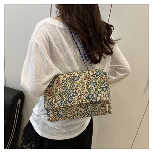Detail der floralen Gobelin-Handtasche mit gewebtem blau-goldenen Kettenriemen