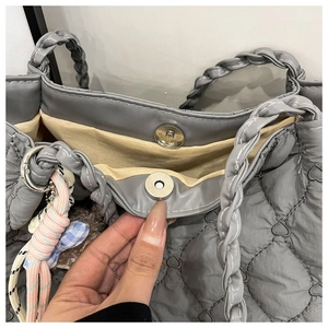 Detail of grey quilted heart pattern tote bag with magnetic closure and rainbow pendant