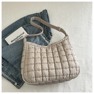 Détail à plat d'un sac cabas matelassé beige avec veste en jean et une carte