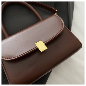 Detailed shot of dark brown matte leather handbag with golden rectangular buckle