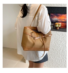 Detail of woven brown tote bag with leather trim and adjustable shoulder strap on model