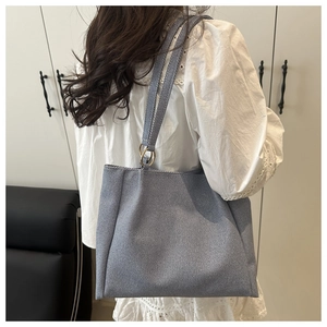 Detail of grey-blue denim tote bag showing thick twill texture and gold metal ring strap attachment