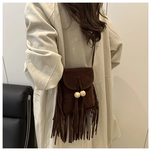 Détail du sac bandoulière en daim marron foncé avec de longues franges et perles