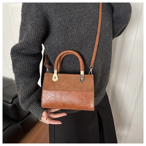 Close-up of brown patchwork leather crossbody bag with woven handle and fashion text detail