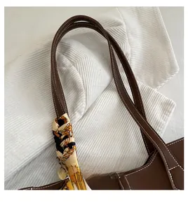 Close-up of dark brown leather handle with white stitching and yellow silk scarf detail