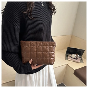 Détail d'une pochette matelassée marron avec finition brillante dans un décor de style